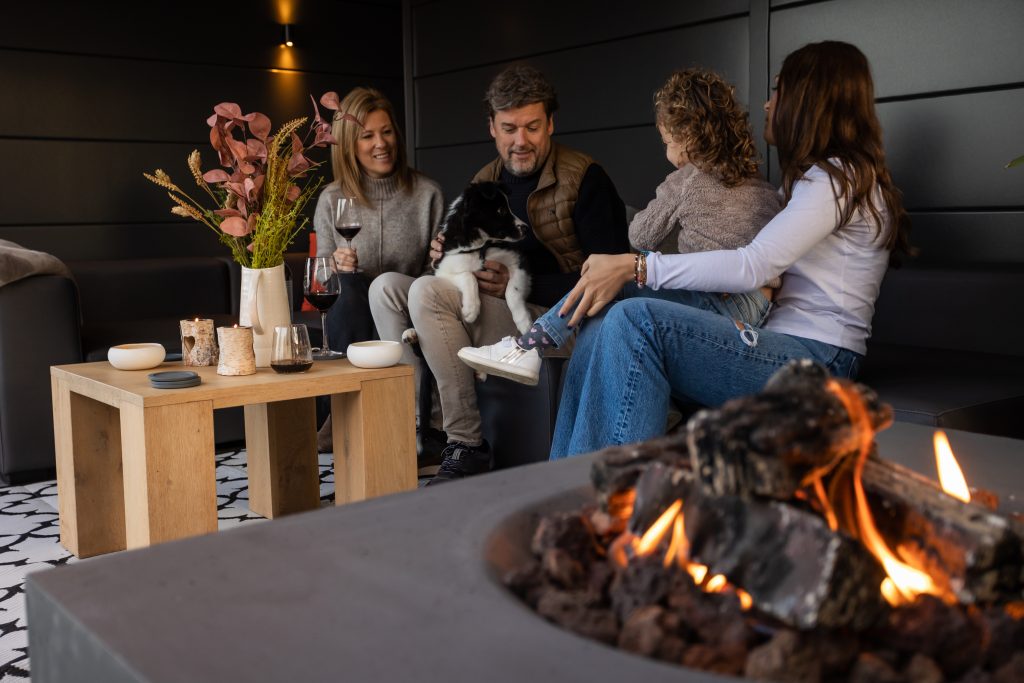 Photo looking into the lounge with a family enjoying a gas fire pit in the Eleganto Lounge 3330 with Extra Large Lounge in Anthracite with Optional Windows