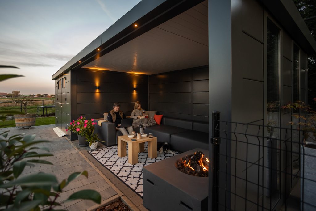 An angled Photo with a couple and fire pit in the Eleganto Lounge 3330 with Extra Large Lounge in Anthracite with Optional Windows
